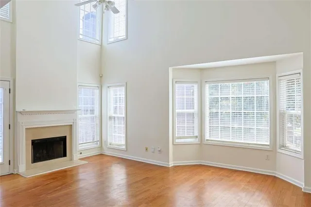 an empty room with wooden floor fireplace and windows