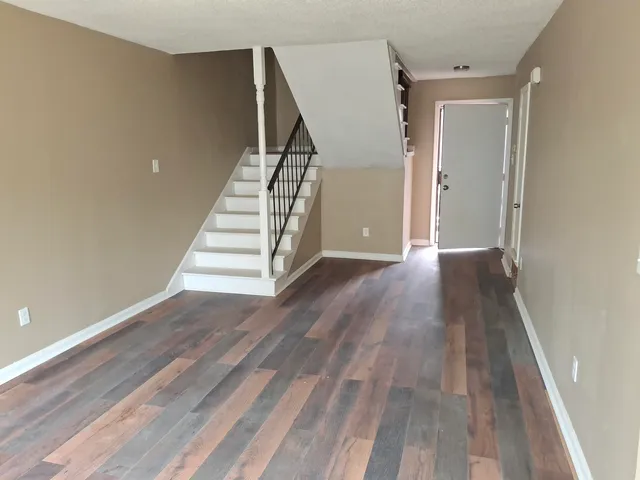 a view of a hallway with wooden floor and stairs