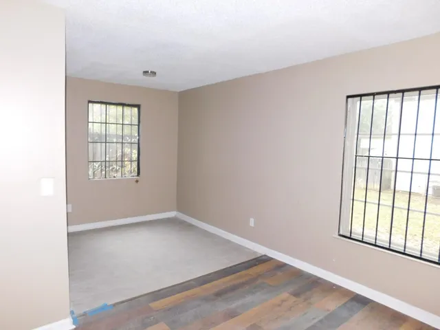 an empty room with wooden floor and windows