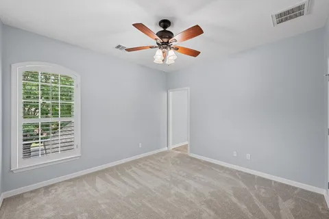 an empty room with ceiling fan and window