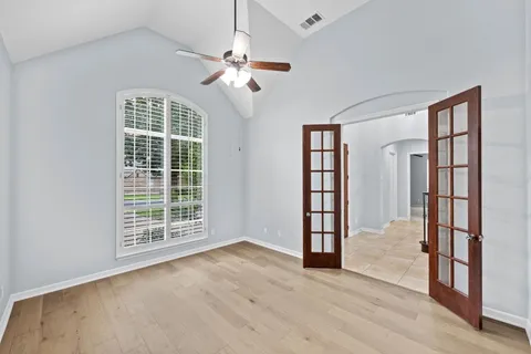 an empty room with wooden floor fan and windows