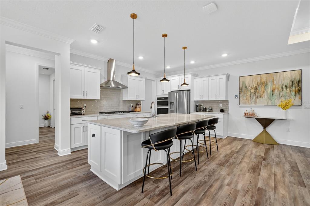 8433 Southwest 98th Terrace Road Ocala, FL 34481 - Photo 13 of 30 a kitchen with stainless steel appliances granite countertop a stove a refrigerator a kitchen island a dining table and chairs with wooden floor