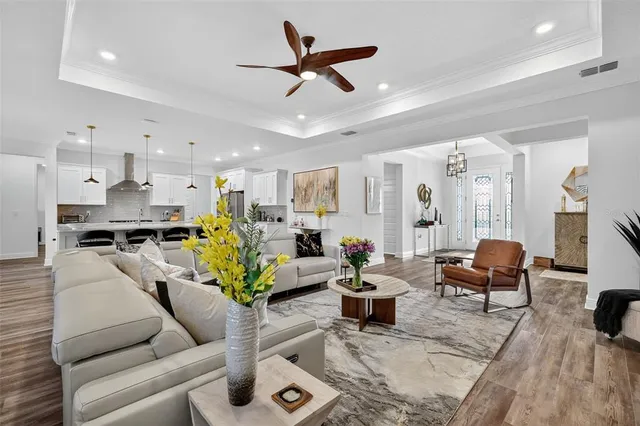 a living room with furniture kitchen view and a chandelier