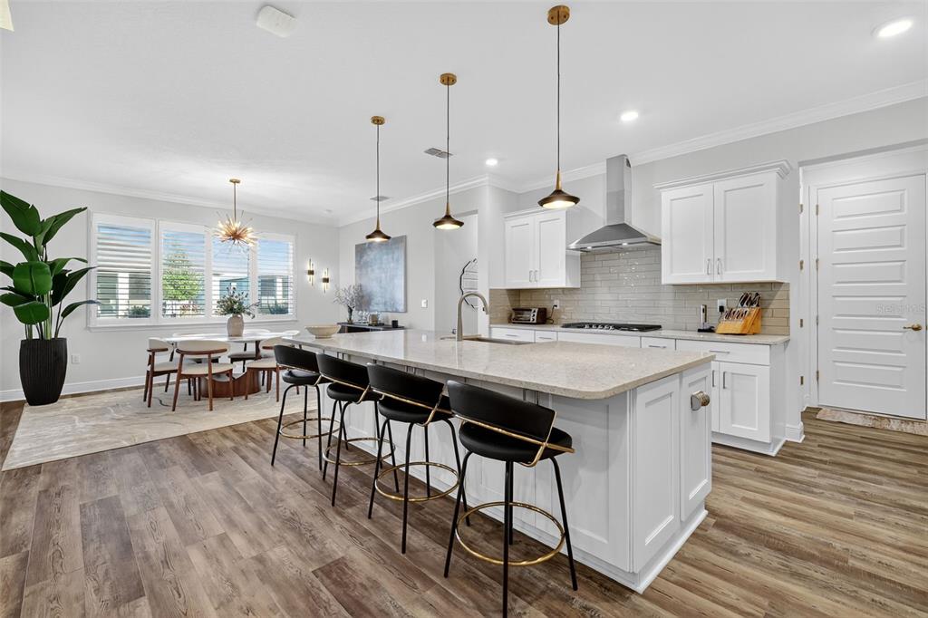 8433 Southwest 98th Terrace Road Ocala, FL 34481 - Photo 10 of 30 an open kitchen with granite countertop a stove a sink a dining table and chairs with wooden floor