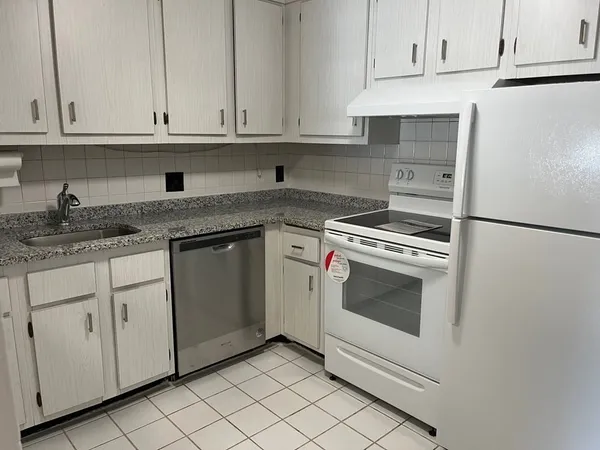 a kitchen with granite countertop white cabinets and white appliances