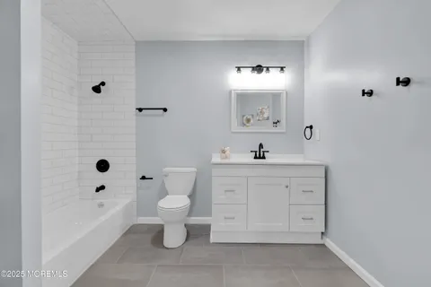 a bathroom with a double vanity sink a toilet a shower and a mirror