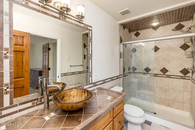 a bathroom with a granite countertop bathtub shower sink mirror vanity and toilet