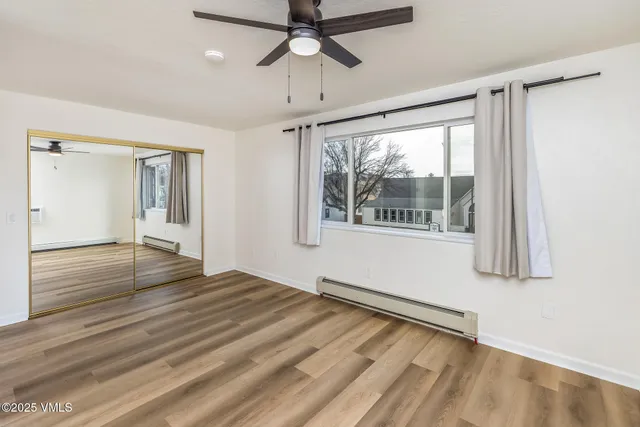 a view of an empty room with a window and wooden floor