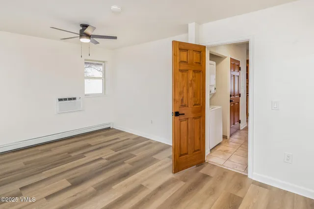 an empty room with wooden floor and a ceiling fan