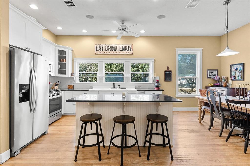 10616 Poe Street Leesburg, FL 34788 - Photo 16 of 54 a kitchen with stainless steel appliances granite countertop wooden floor window and refrigerator