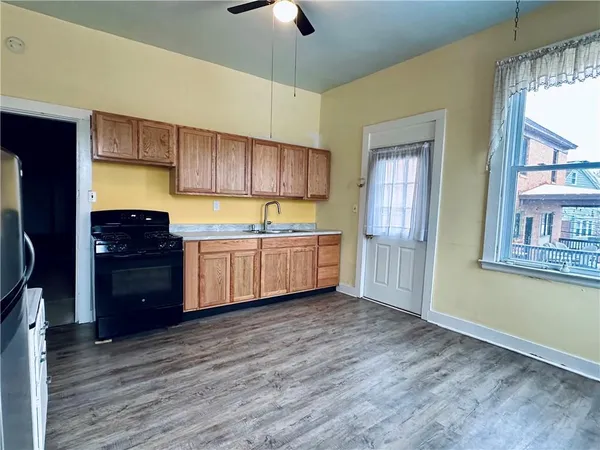 a kitchen with stainless steel appliances granite countertop a stove a sink and a refrigerator with wooden floors