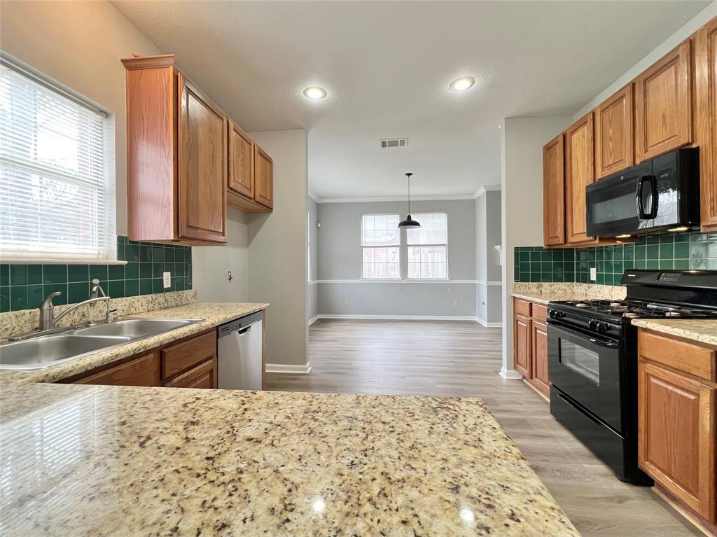 1809 Springwater Drive Round Rock, TX 78681 - Photo 7 of 25 Kitchen featuring black appliances, decorative backsplash, wood finish cabinets, and ornamental molding