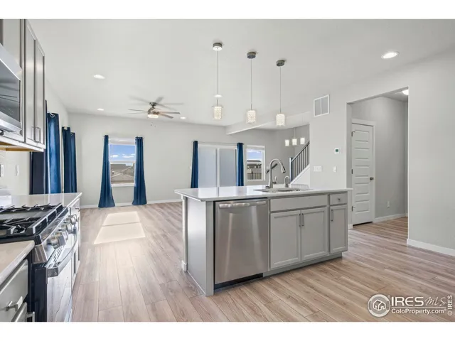 a large kitchen with stainless steel appliances a large counter top a sink a stove and a refrigerator