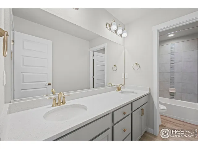 a bathroom with a sink double vanity granite tub shower and a mirror