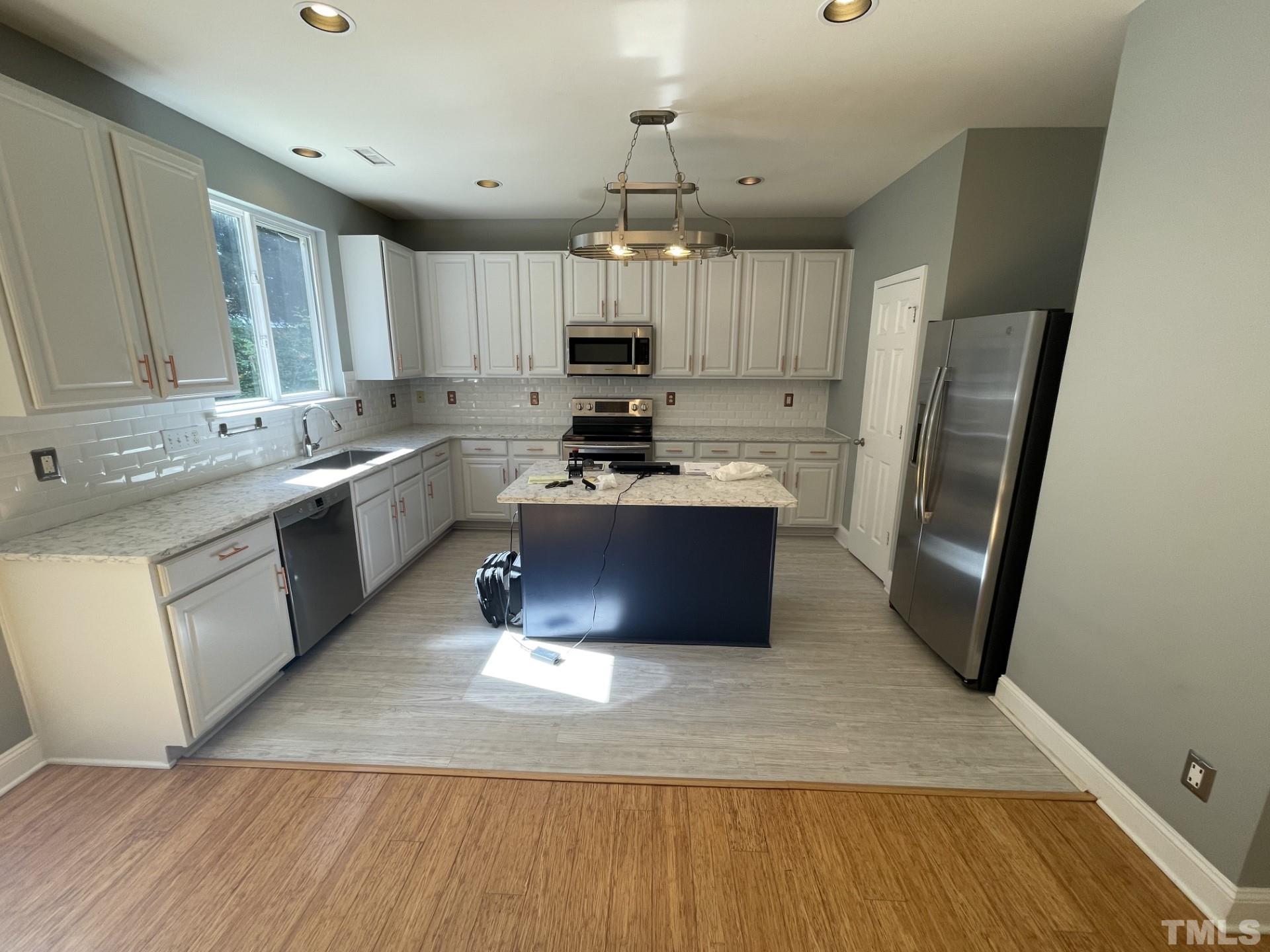 152 Solheim Lane Raleigh, NC 27603 - Photo 6 of 25 a large kitchen with stainless steel appliances a stove a sink dishwasher a refrigerator and a oven with wooden floor