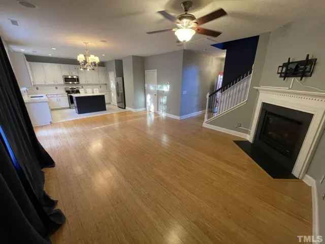 an open kitchen with granite countertop kitchen island a stove a sink dishwasher and a fireplace with wooden floor