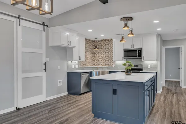 a kitchen with kitchen island granite countertop a sink appliances and cabinets