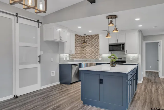 a kitchen with kitchen island granite countertop a sink appliances and cabinets