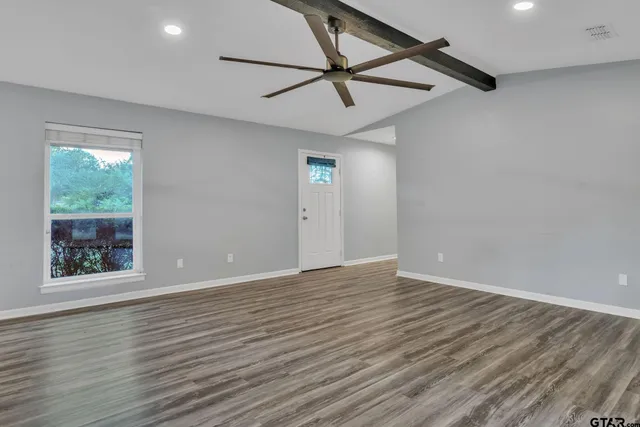 a view of an empty room with window and wooden floor