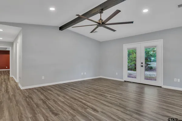 an empty room with wooden floor and windows
