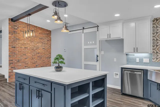 a kitchen with stainless steel appliances kitchen island a table chairs in it and wooden floors