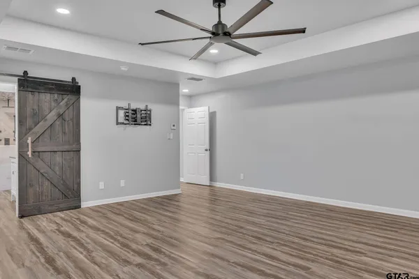 an empty room with wooden floor and fan