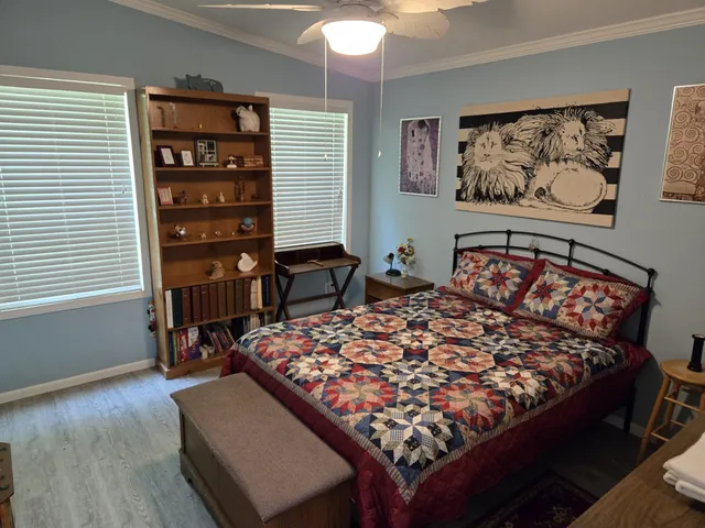 a bed sitting in a bedroom next to a window with a bookshelf
