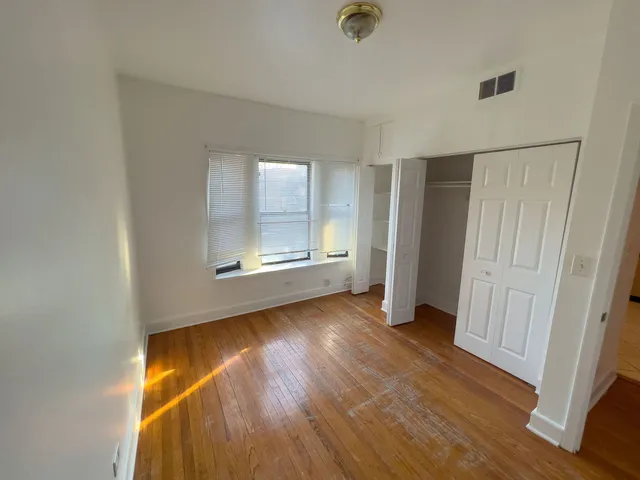 an empty room with wooden floor cabinet and windows