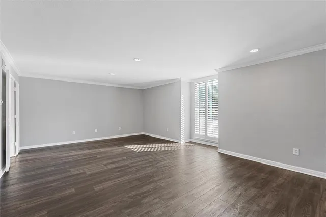 a view of an empty room with wooden floor and windows