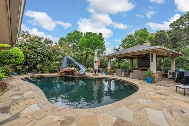 a view of a swimming pool with lawn chairs under an umbrella