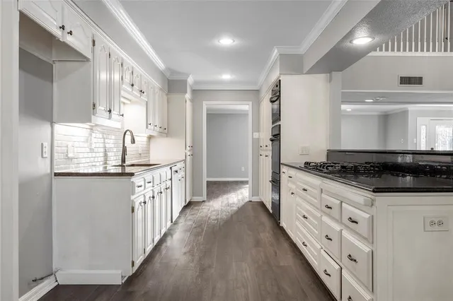 a kitchen with granite countertop a sink stove and cabinets