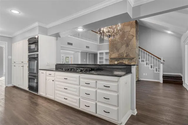 a kitchen with granite countertop a white stove top oven and a dishwasher with white cabinets