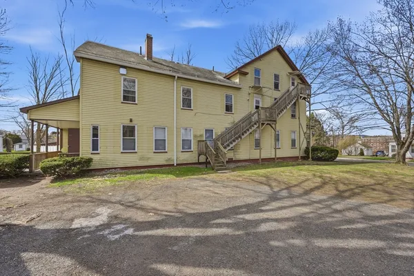 a view of a house with a yard and large tree