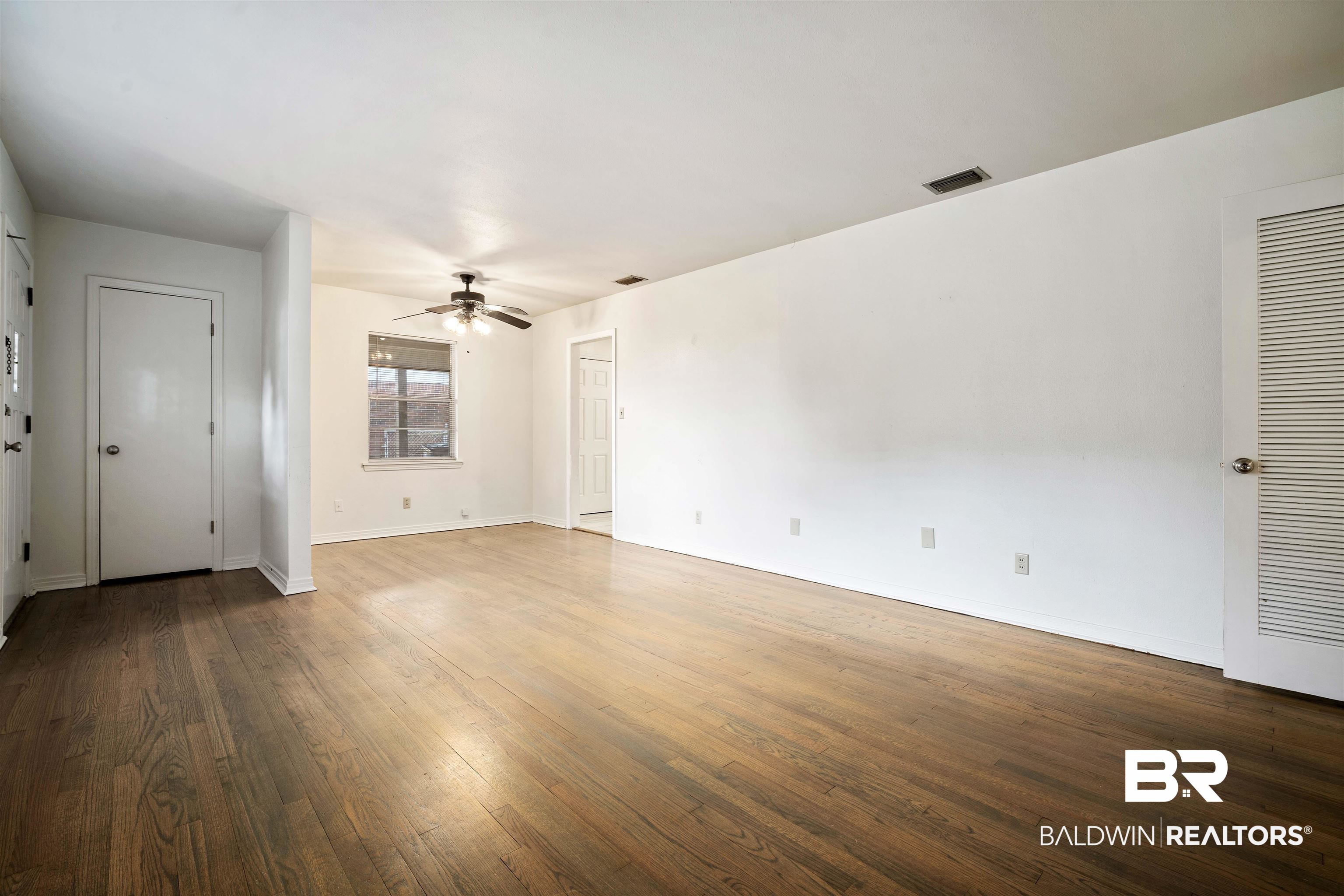 570 Markham Drive Mobile, AL 36609 - Photo 11 of 25 Unfurnished living room featuring dark wood-type flooring, visible vents, baseboards, and ceiling fan