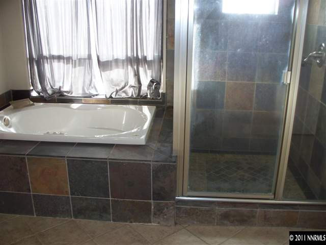4891 Rancheria Road Fallon, NV 89406 - Photo 6 of 13 a bathroom with a granite countertop sink a window and a glass door shower