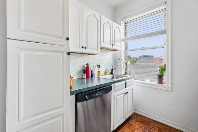 a kitchen with white cabinets and window
