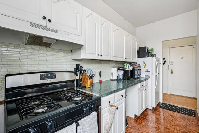 a kitchen with stainless steel appliances granite countertop a stove and white cabinets