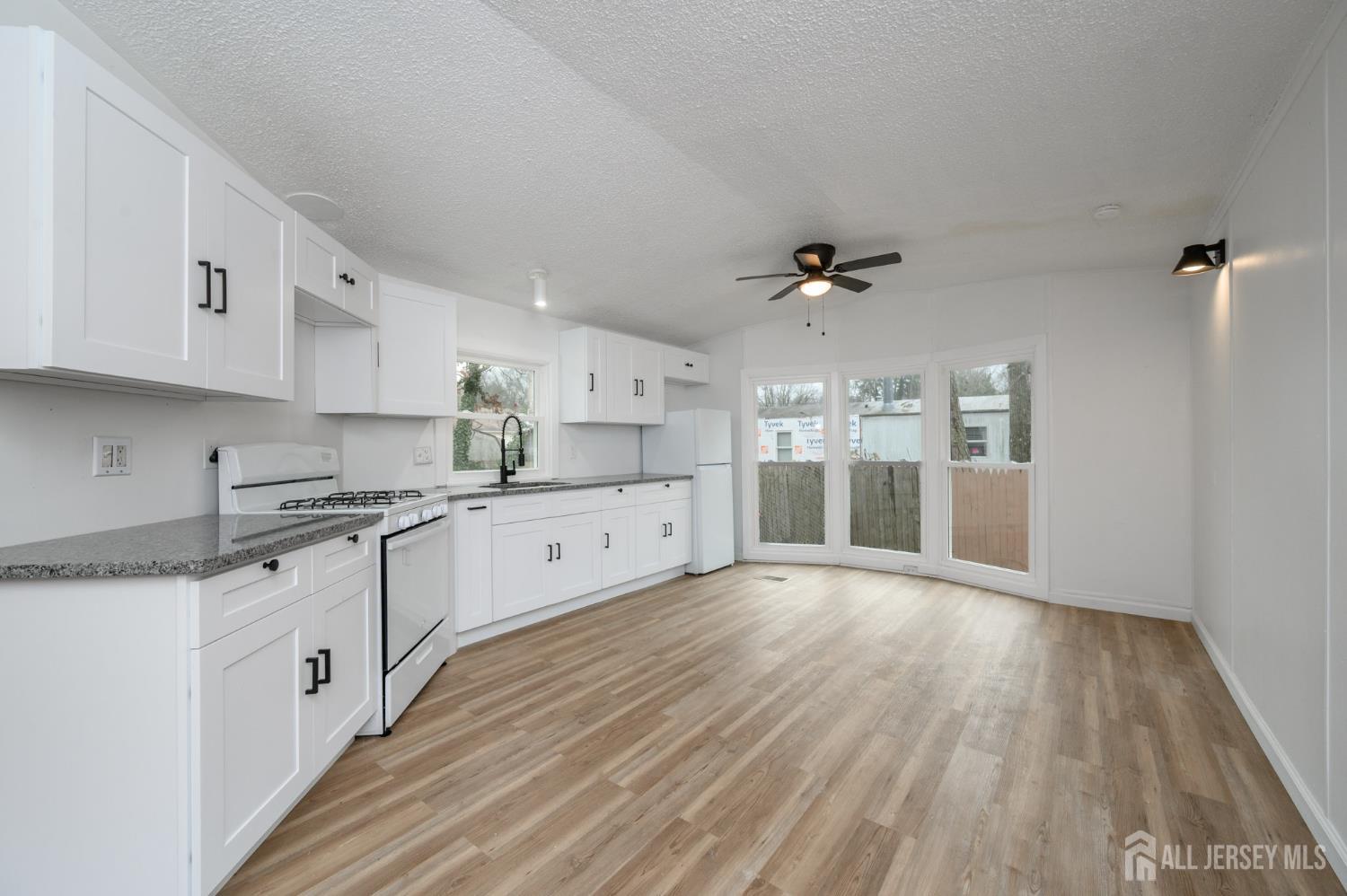 448 Evergreen Road Millville, NJ 08332 - Photo 3 of 29 a large white kitchen with a sink dishwasher a stove and white cabinets with wooden floor
