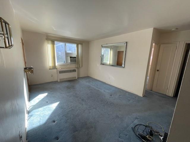 216-21 73rd Avenue, Unit 1 Queens, NY 11364 - Photo 7 of 12 Unfurnished living room featuring cooling unit, radiator heating unit, and carpet floors