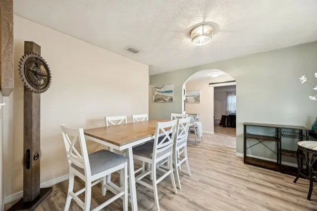 a kitchen with stainless steel appliances granite countertop a stove top oven a sink dishwasher a refrigerator and a dining table with wooden floor