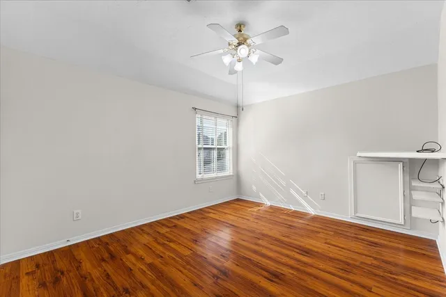 a view of an empty room with window and wooden floor