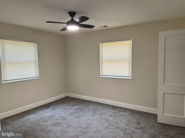 an empty room with windows and fan