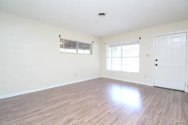 an empty room with wooden floor and windows