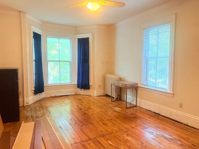 a view of an empty room with a window and wooden floor