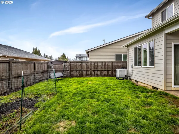 a view of a backyard with plants and large trees