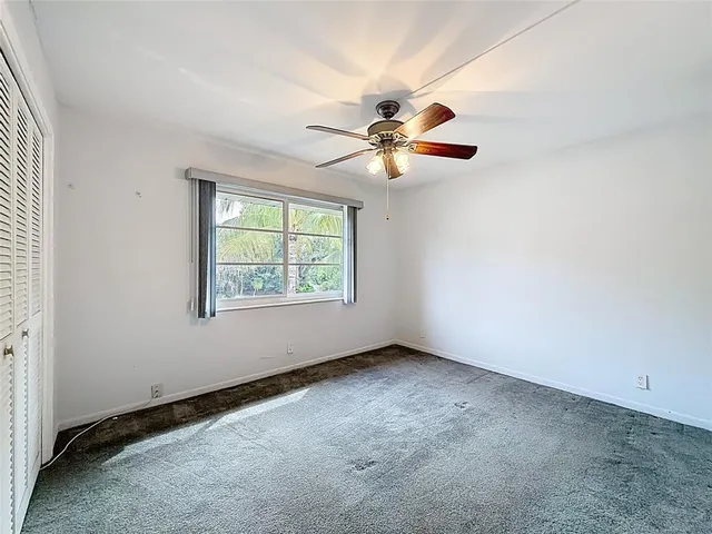 an empty room with windows and fan