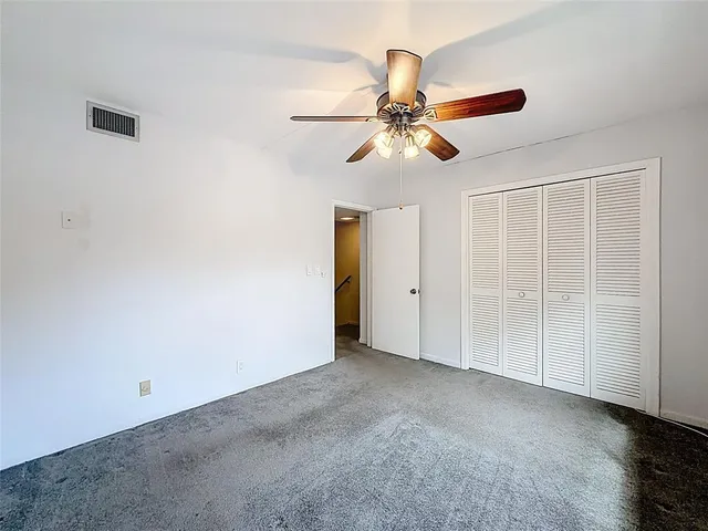 an empty room with closet and a ceiling fan