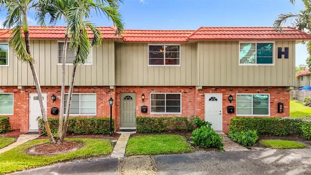 a front view of a house with a yard and potted plants