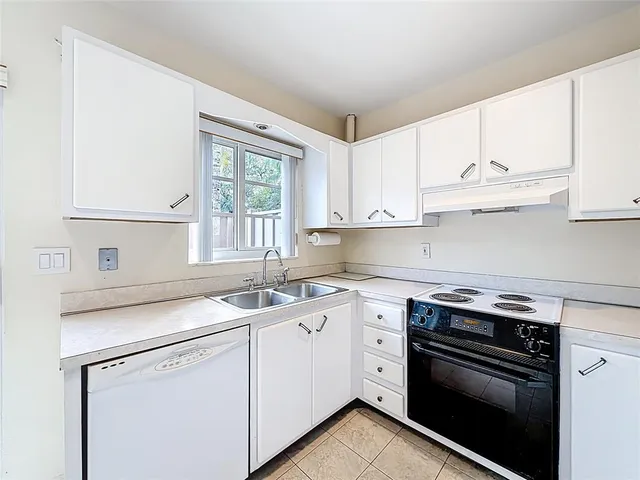 a kitchen with cabinets appliances a sink and a window
