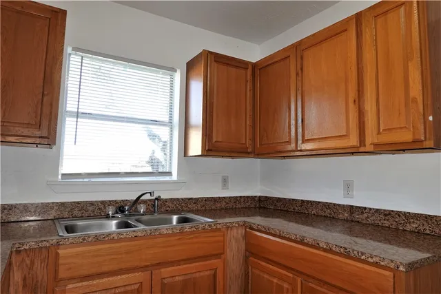 a kitchen with stainless steel appliances granite countertop white cabinets window and a sink
